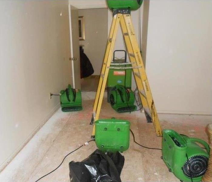 picture of green air movers and a yellow ladder drying a room